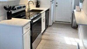 Une cuisine moderne avec des meubles blancs, une cuisinière en acier inoxydable, un four à micro-ondes et un réfrigérateur.