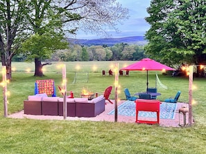 An outdoor seating area with a fire pit, chairs, and a red umbrella.