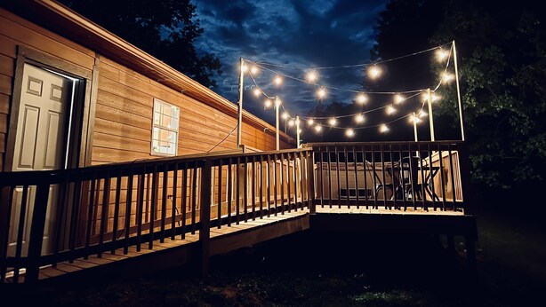 Una cabana de fusta amb terrassa de fusta i llums enfilades.