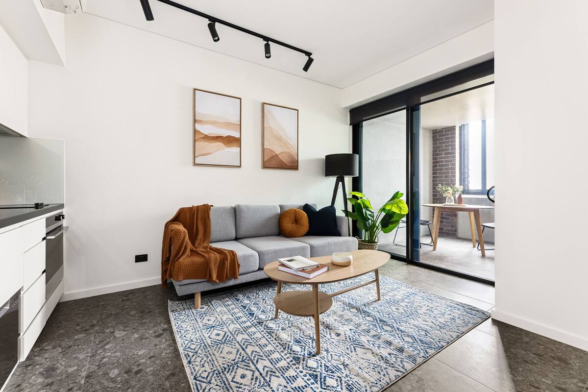 A modern living room with a grey sofa, a coffee table, and a patterned rug.