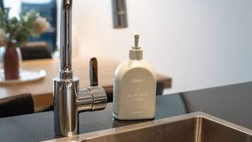 Un évier de cuisine moderne, doté d’un robinet chromé et d’un distributeur de savon blanc portant l’inscription « ZERO CO, donnez un coup de pouce à la planète ».