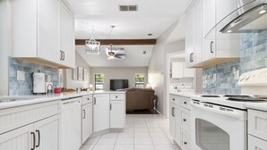 A modern kitchen with white cabinetry, a built-in oven, and a large window. - ⚓Jerry's Gem! Beautiful private pool home near Anna Maria Island!⚓🌅 (Bradenton)