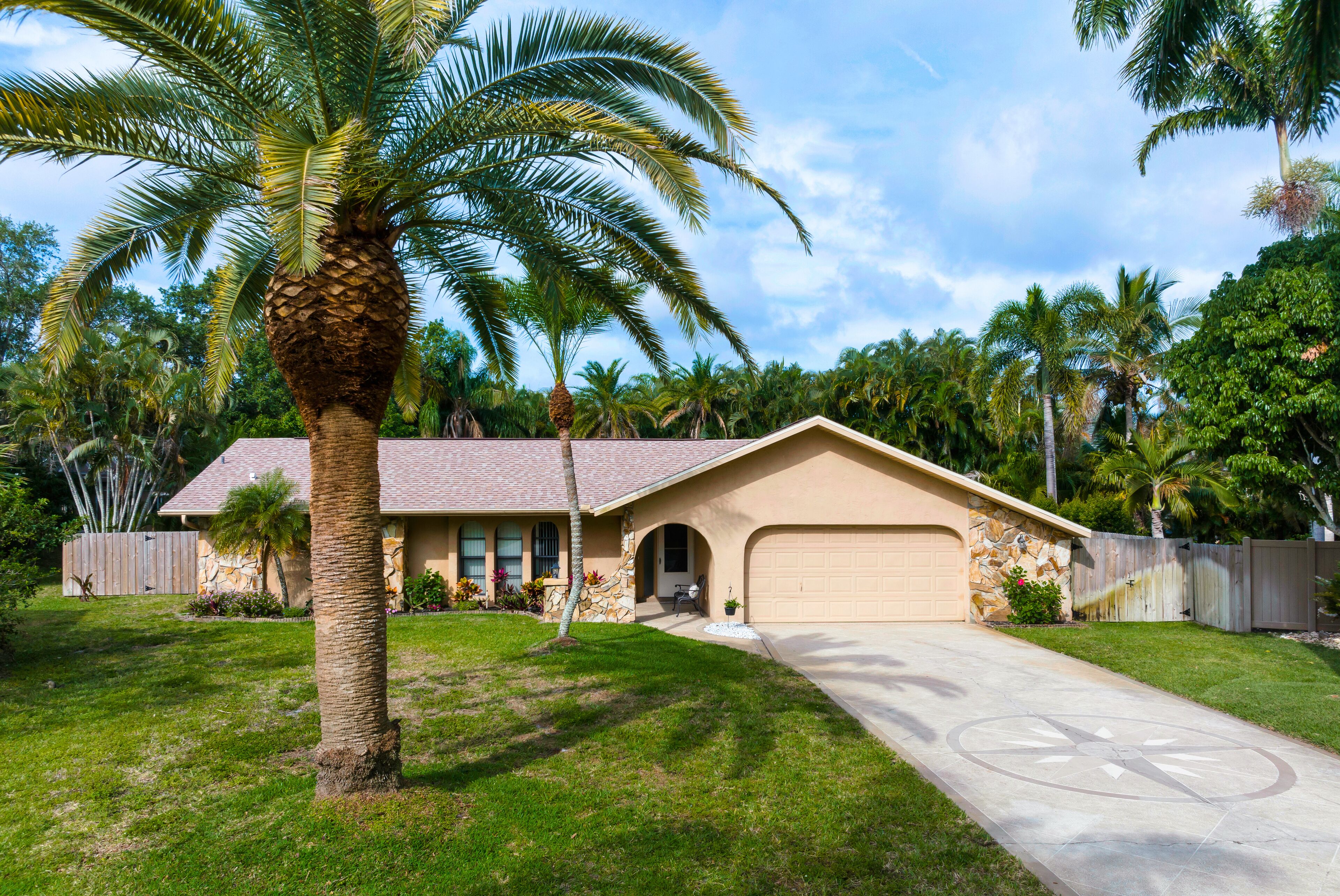 A single-story house with a garage, a stone exterior, and a well-maintained lawn.