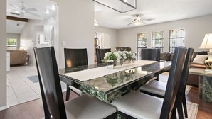 A spacious dining area with a marble table, dark chairs, and a ceiling fan. - ⚓Jerry's Gem! Beautiful private pool home near Anna Maria Island!⚓🌅 (Bradenton)