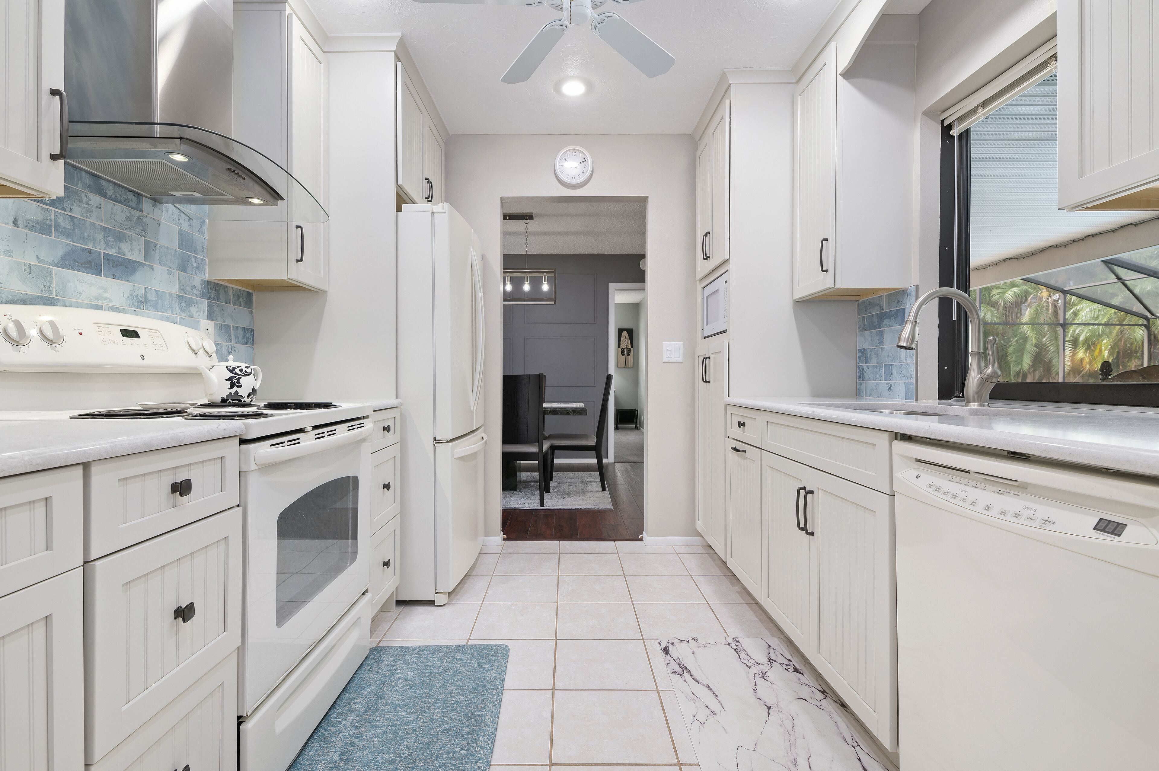 Een moderne keuken met witte kastjes, een roestvrijstalen afzuigkap en een inbouw vaatwasser.