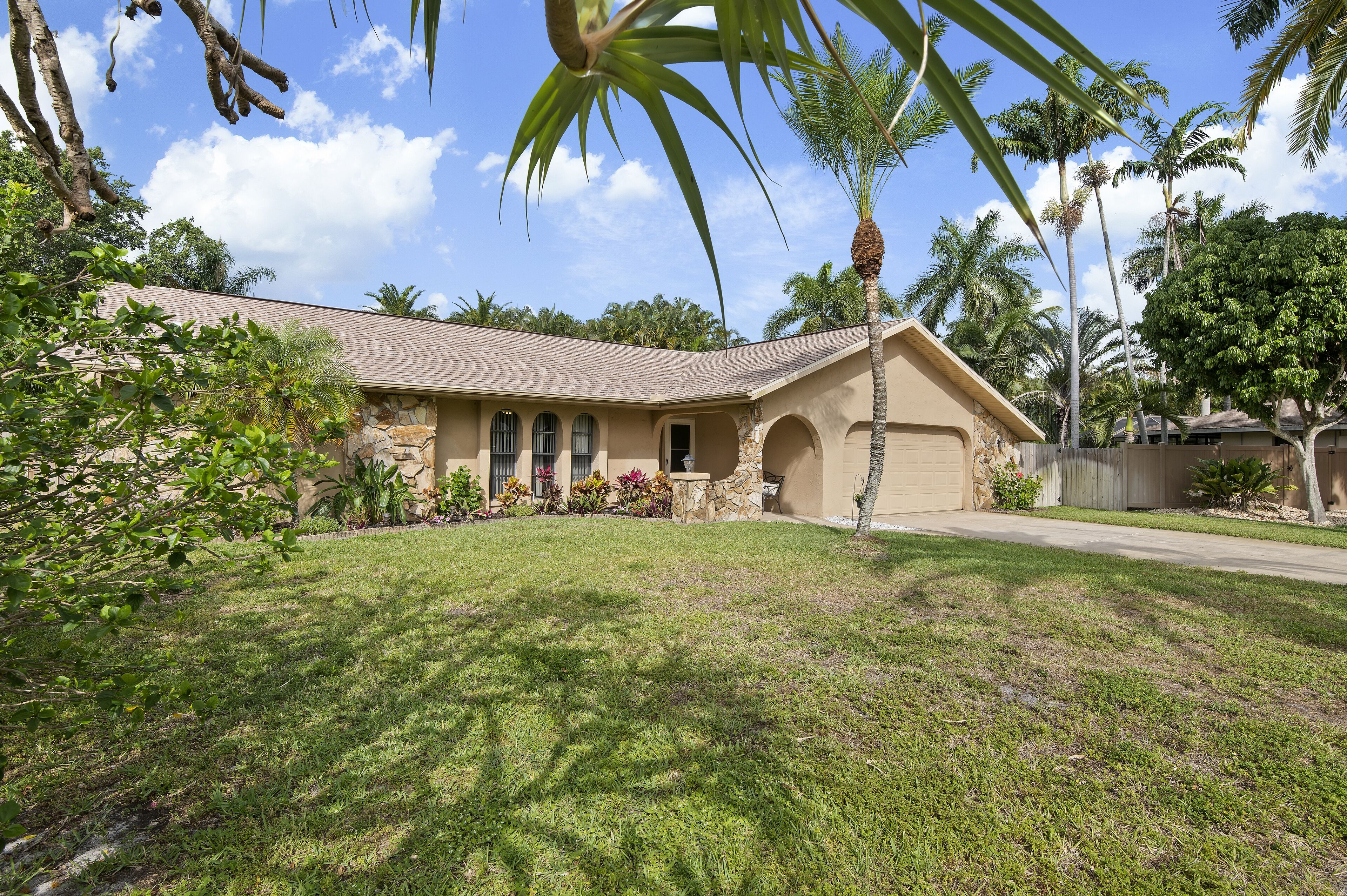 A single-story house with a stone facade, a tiled roof, and a well-maintained lawn.