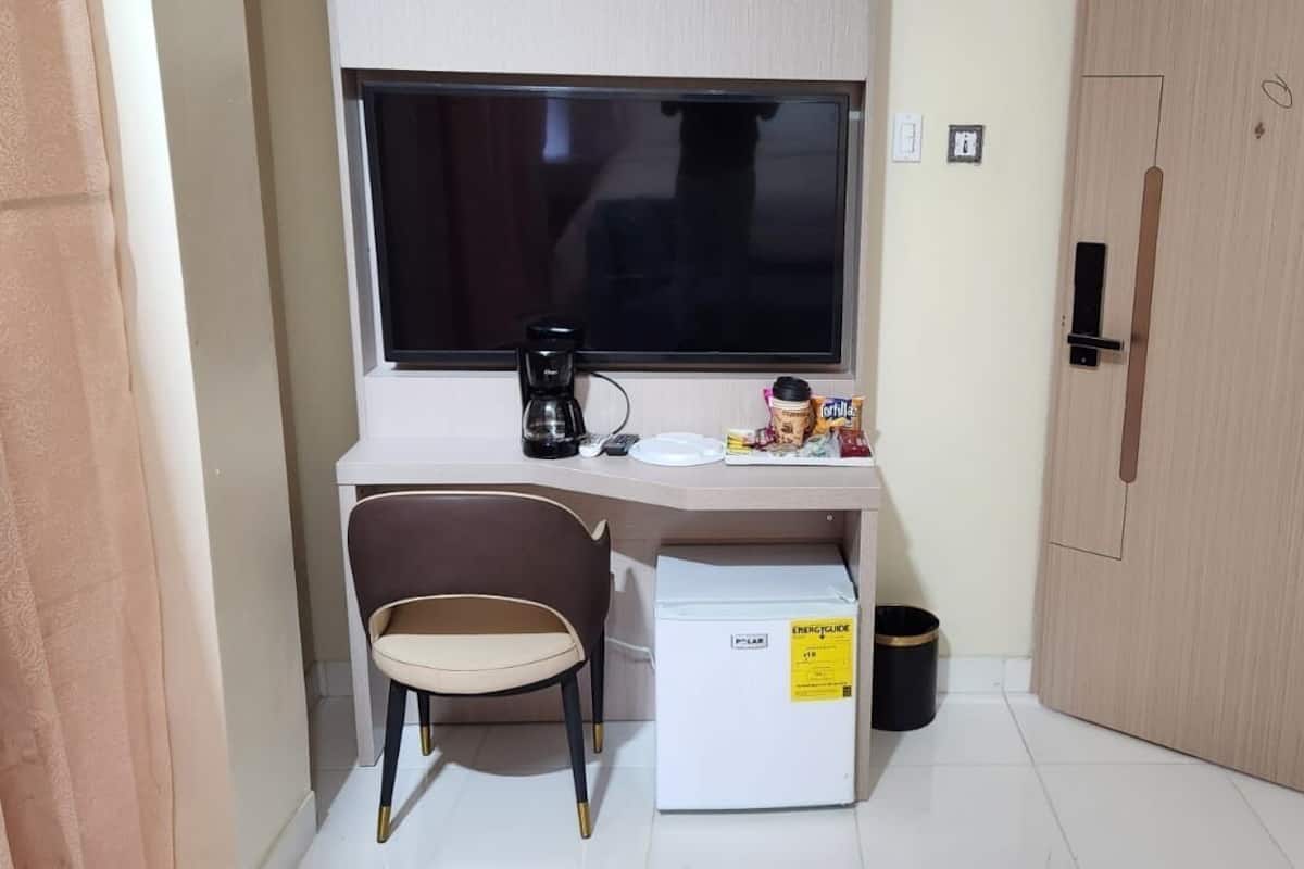 A small kitchenette with a refrigerator, a coffee maker, and a chair.