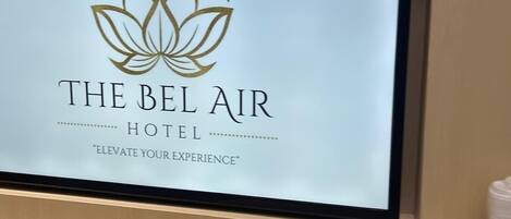 Un comptoir d’accueil d’hôtel avec une enseigne indiquant « The Bel Air Hotel » et un logo représentant une fleur de lotus.