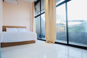 A bedroom with a bed, a window with a curtain, and a view of the outside.
