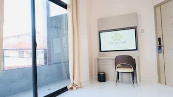 Ein Hotelzimmer mit großem Fenster, einem gerahmten Schild an der Wand, einem Sessel und einer Tür.