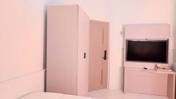 A bedroom with a bed, a wardrobe, a TV, and a small table with a cup and snacks.