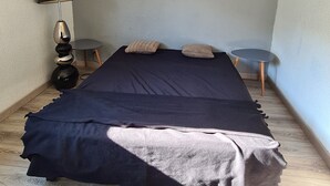 Ein Schlafzimmer mit einem Bett, Kissen, einer Lampe und einem kleinen Tisch.
