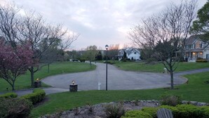A residential driveway with a curved path, a stone lamp post, and a bench. - Spacious home near Aquarium & heart of wine country Shopping & close to Hamptons (Riverhead)