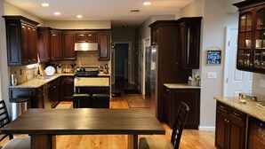 A modern kitchen with dark wood cabinets, granite countertops, and stainless steel appliances. - Spacious home near Aquarium & heart of wine country Shopping & close to Hamptons (Riverhead)