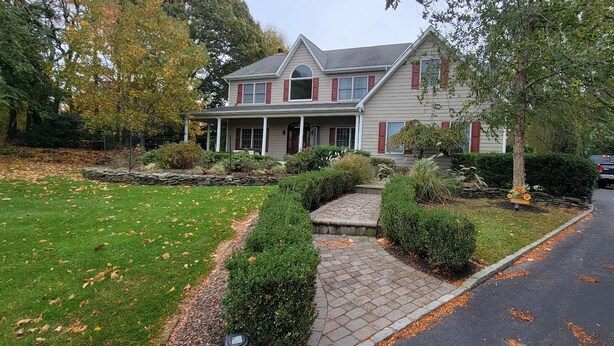 A two-story house with a covered porch, a stone pathway leading to the entrance, and a driveway with a parked SUV. - Spacious home near Aquarium & heart of wine country Shopping & close to Hamptons (Riverhead)