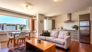 A modern kitchen with a built-in oven, a refrigerator, and a dining area with a table and chairs.