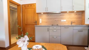Une cuisine de taille réduite avec des meubles gris, un plan de travail en bois et un évier.