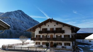 A two-story chalet with a balcony, wooden shutters, and a snow-covered mountain in the background. - 4 Fewo , Balkon, Kochnische, 1 Schlaf- und 1 Wohn-/schlafz. max 4 Pers, Wlan (Ruhpolding)