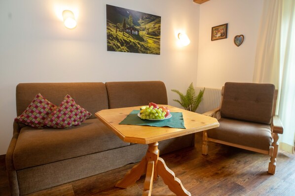Ein gemütliches Wohnzimmer mit einem Holztisch, einem braunen Sofa und einem braunen Sessel.
