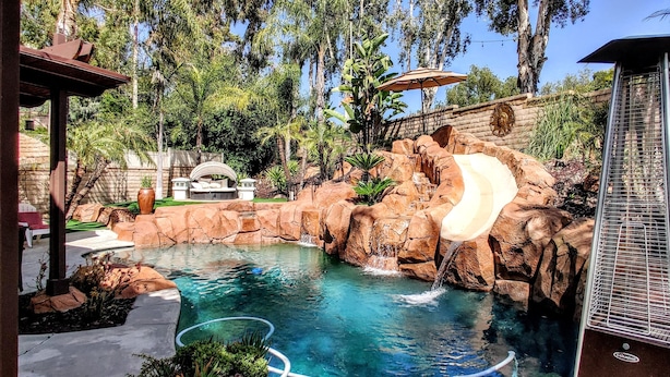 Una piscina amb cascada, envoltada de roques i vegetació.