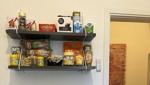 A kitchen with shelves stocked with coffee, tea, and condiments. - Cristina Garden (Pisa)
