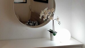 A round mirror on a white desk with a potted orchid and a framed picture on the wall. - Cristina Garden (Pisa)