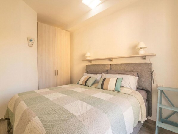Une chambre à coucher avec un lit, une armoire, une table de chevet et une lampe.