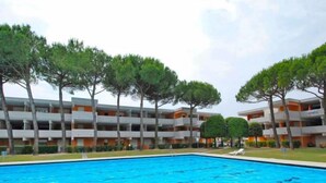 Une piscine entourée d’immeubles à plusieurs étages dotés de balcons, d’arbres et surplombant un ciel dégagé.