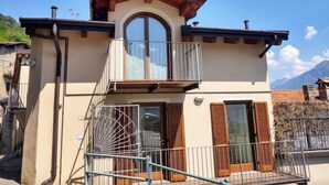A two-story building with a balcony, a large arched window, and wooden shutters.
