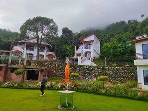 A residential area with houses, a grassy lawn, and a stone wall.