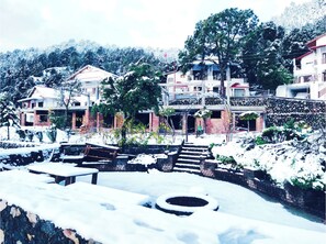 A residential area with houses, a stone wall, and a snow-covered ground.