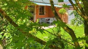 Een traditioneel Japans gebouw met een houten gevel, een pannendak en een kleine tuin met een tafel en stoelen.