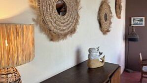 Ein Zimmer mit einer dunklen Holztruhe, Wanddekoration aus gewebtem Material und einer kleinen Walsskulptur.