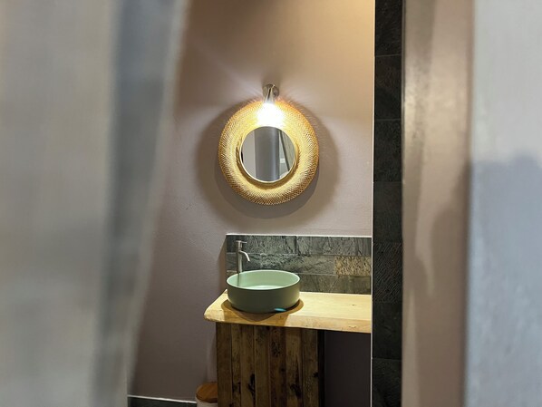 A bathroom with a round mirror, a wooden stool, and a sink. - Villa La Pointe. 3 bedrooms. Swimming pool and ocean view. 600 meters from the Saline Lagoon. (Saline les bains)
