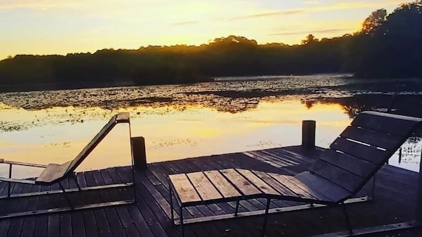 A wooden deck with two lounge chairs facing a calm body of water during sunset. - MATOUNE pleasant, 4/6 person house near Lake Leon  (Léon)
