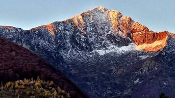 A mountain with snow patches and a forested area in the foreground.