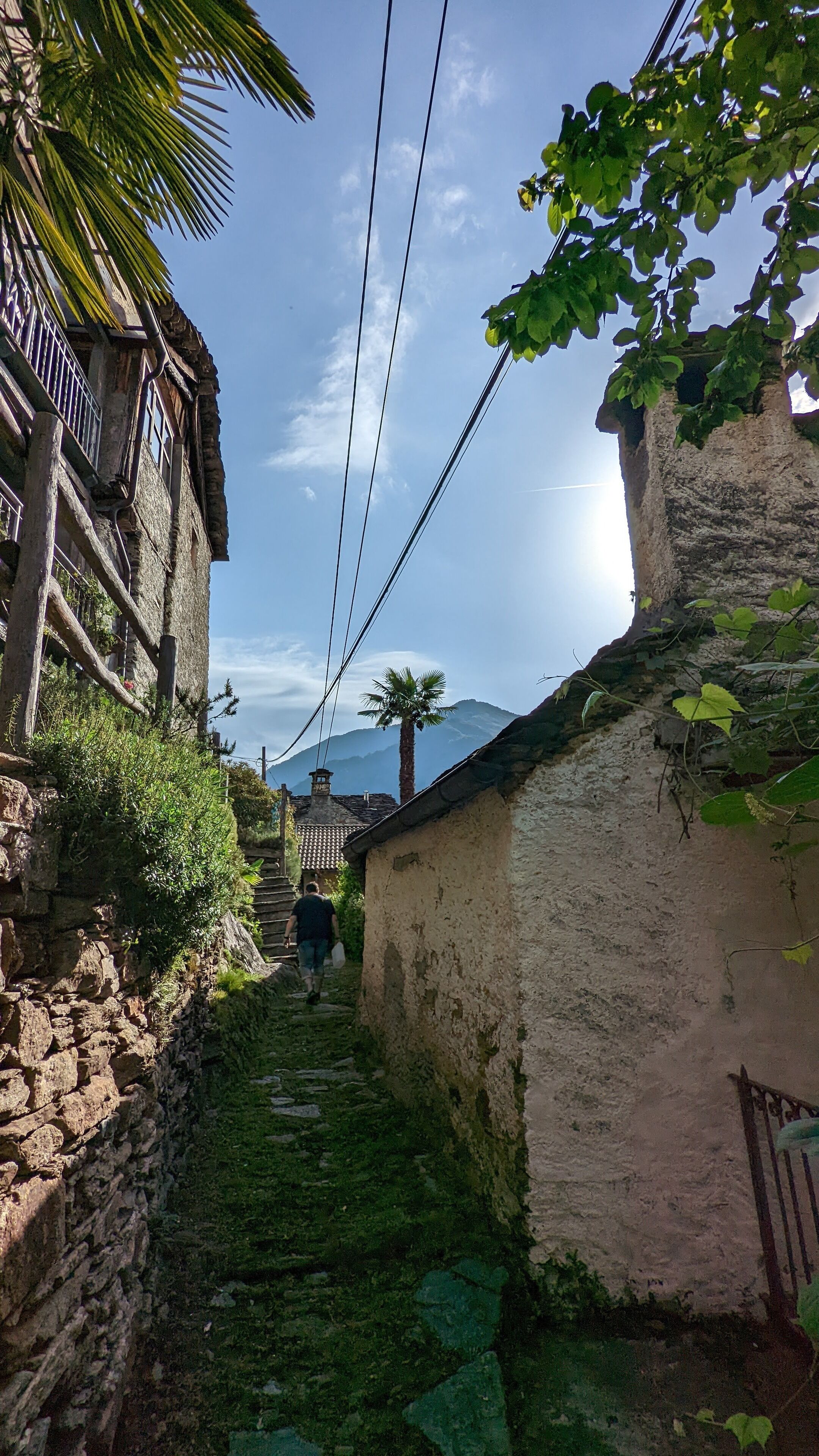 A narrow alleyway with stone walls and a wooden building on the left.