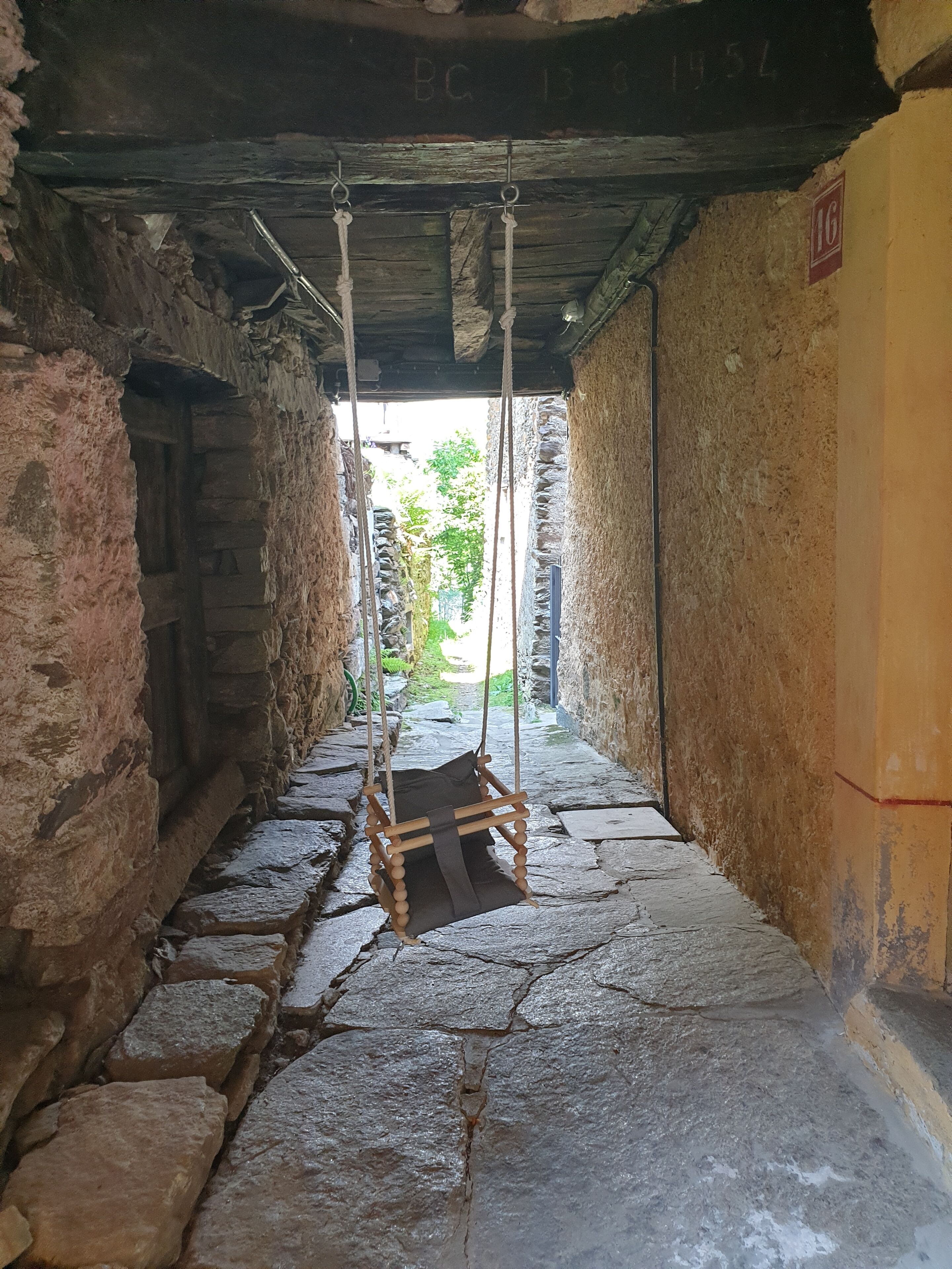 Un estrecho pasillo de piedra con un columpio de madera rústica.