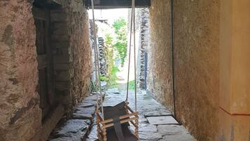 Un estrecho pasillo de piedra con un columpio de madera rústica.