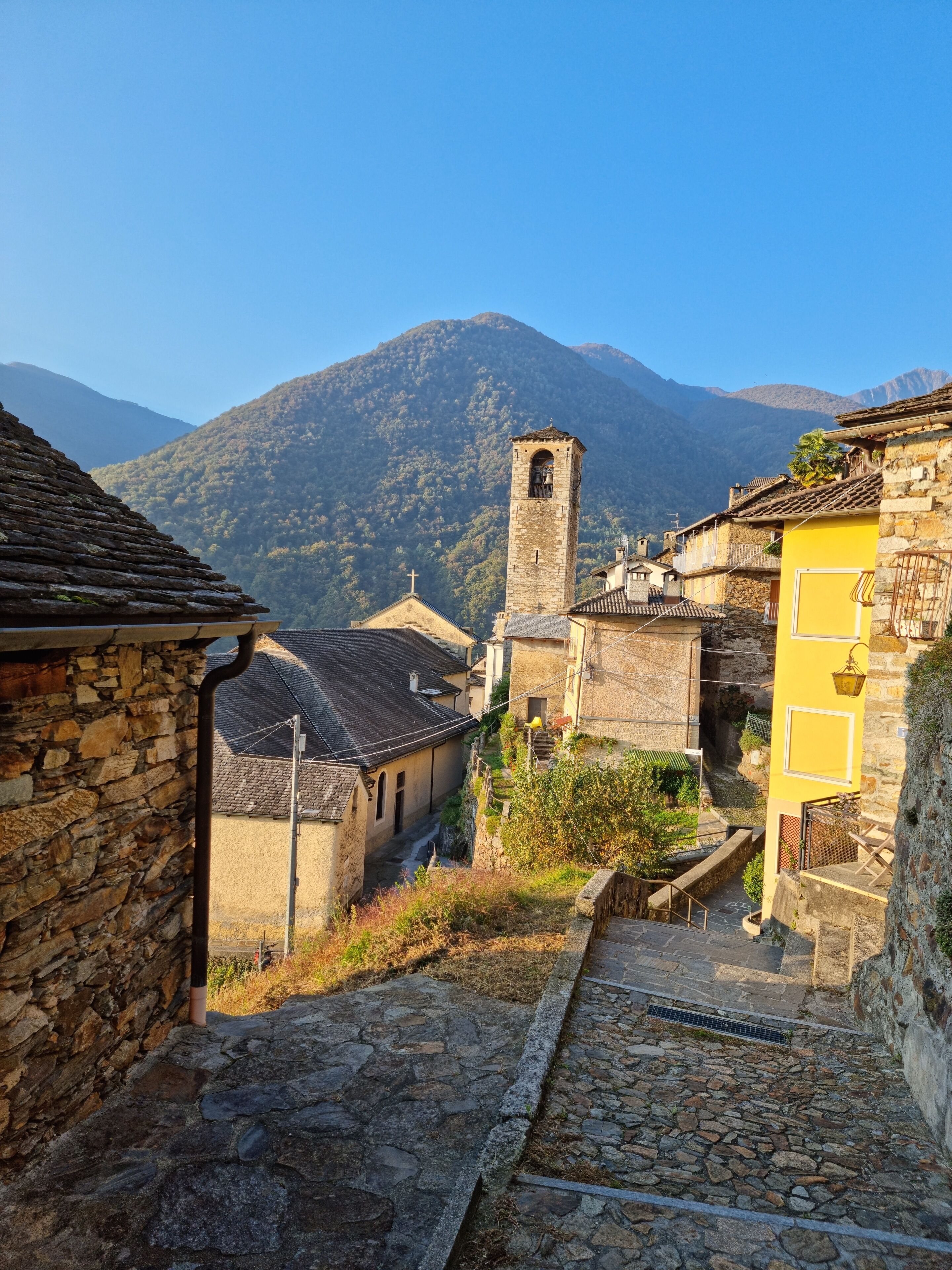 A stone staircase leading up to a village with traditional buildings and a church tower.