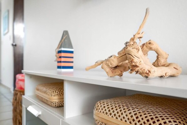 Una estantería blanca con una raíz de ginseng decorativa y un objeto a rayas.