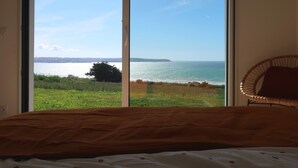 A bedroom with a large window overlooking a coastal view.