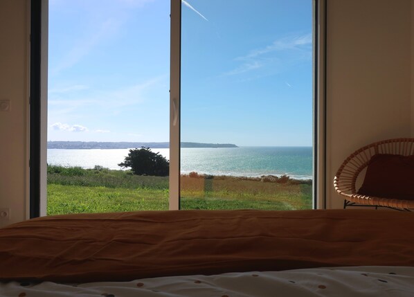 Un dormitorio con un amplio ventanal con vistas a la costa.