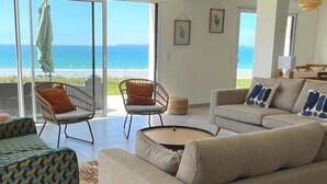 A spacious living room with a large sliding glass door leading to a balcony overlooking the sea.