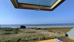 A room with a skylight overlooking a beach.