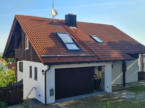 Ein modernes, zweistöckiges Haus mit Schrägdach, Garage und Satellitenschüssel.