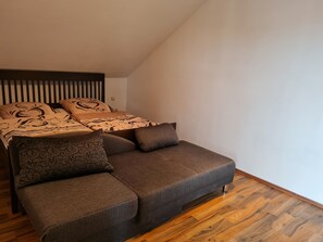 Ein Schlafzimmer mit einem Bett, einem Sofa und Holzboden.