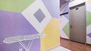 A hallway with a geometric-patterned wall, a door labeled 113, and a white ironing board.