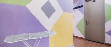 A hallway with a geometric-patterned wall, a door labeled 113, and a white ironing board.