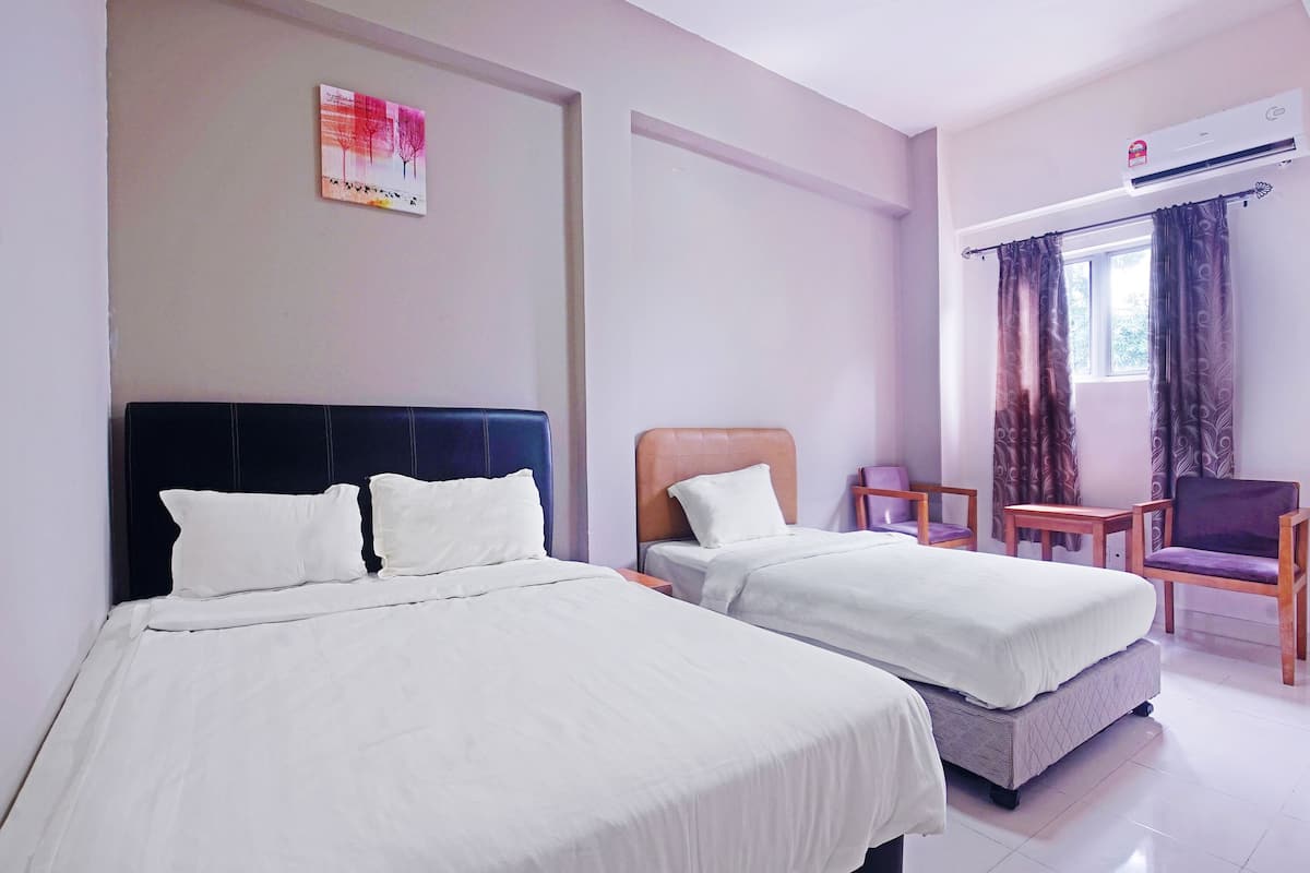 A hotel room with two beds, a chair, a table, and an air conditioning unit.